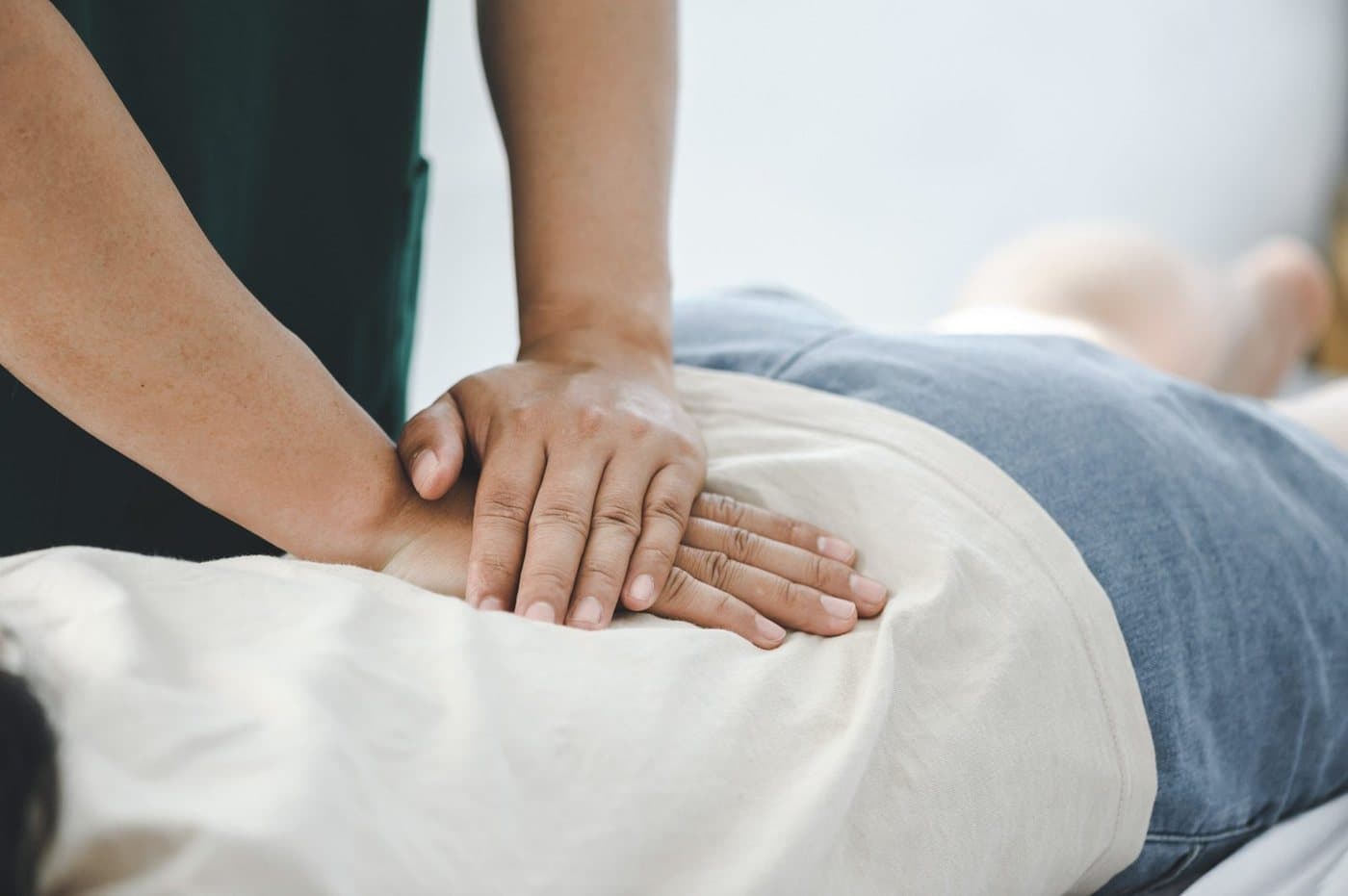 A physical therapist's hands applying manual therapy to a patient's lower back